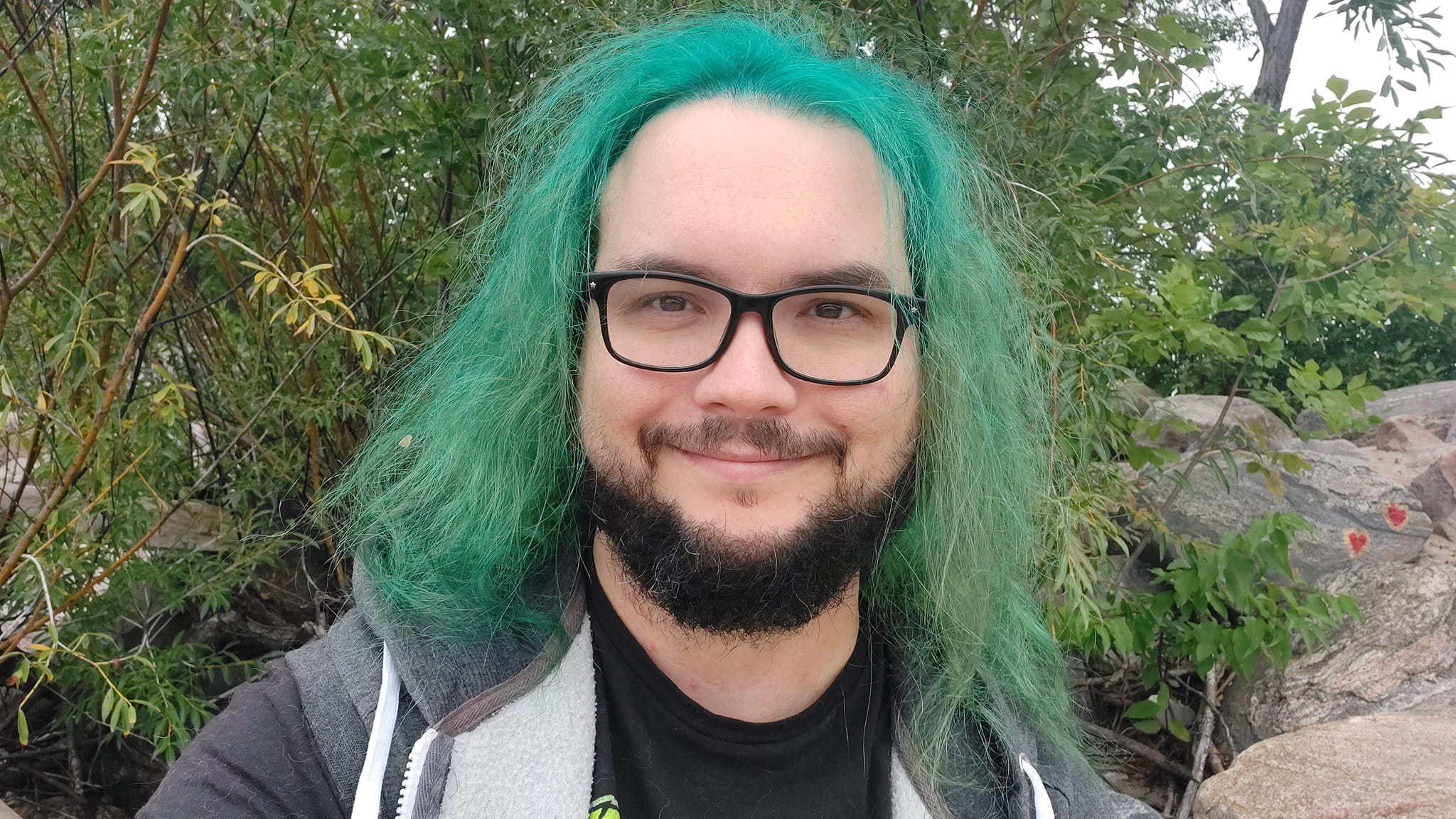 A man with green hair stands outside at a boulder breakwater, photo 8